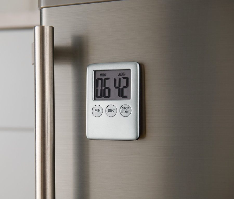 Un minuteur numérique est fixé sur un réfrigérateur en métal.