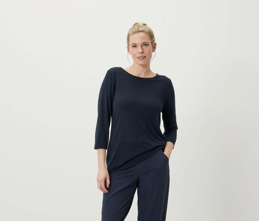 Femme posant dans un t-shirt à manches trois-quarts bleu marine et un pantalon.