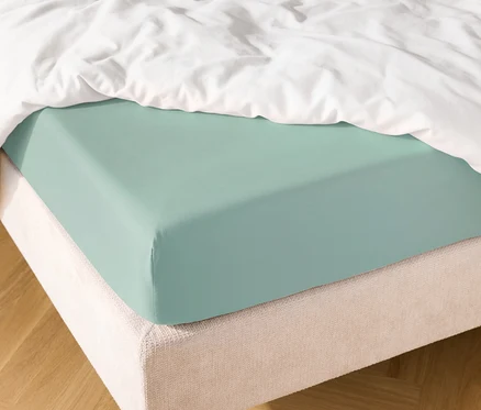 Lit avec drap-housse bleu clair et couette blanche.