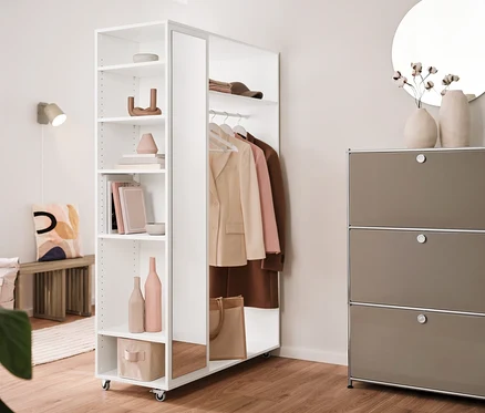 Intérieur avec une lampe murale en métal crème, une étagère en métal « CN3 » à 3 abattants et une garde-robe mobile avec miroir.