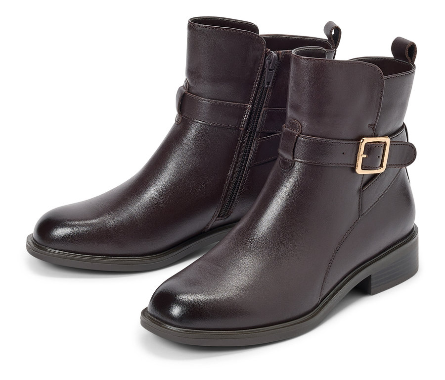 Deux bottines marron avec boucle et fermeture éclair posées sur un fond blanc.