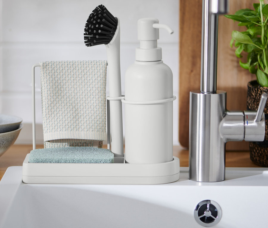 Organisateur d’évier avec brosse, chiffon et distributeur de savon près de l’évier.