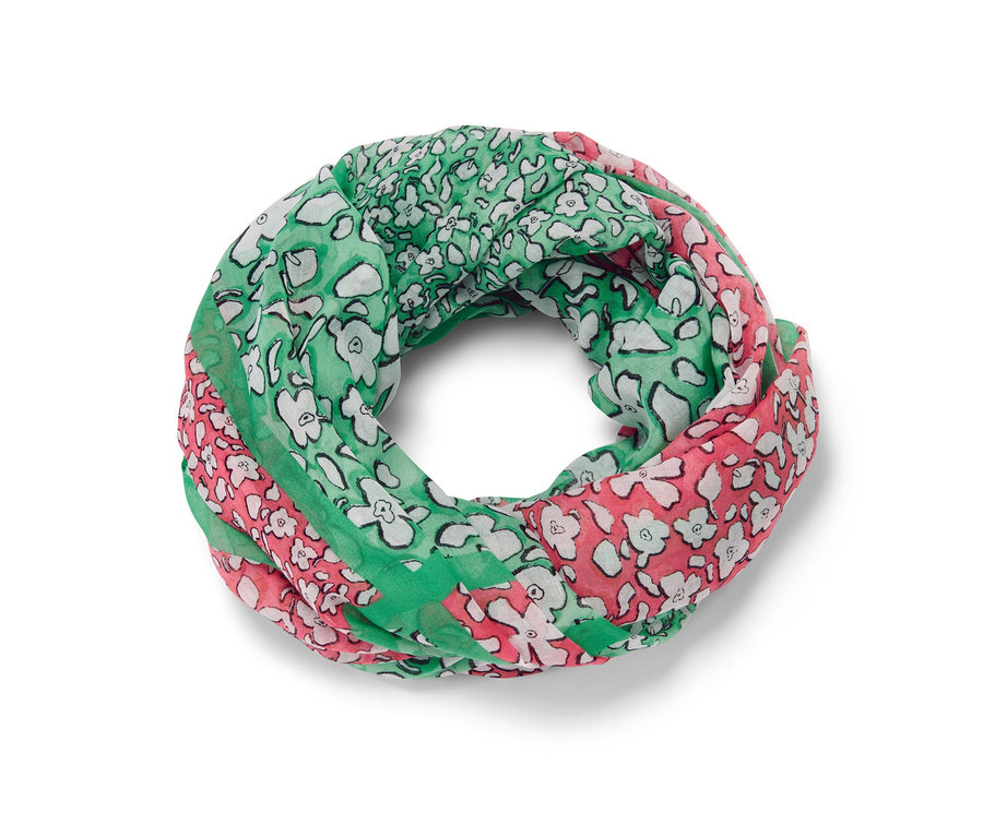 Un foulard loop imprimé en vert, rose et blanc est posé.