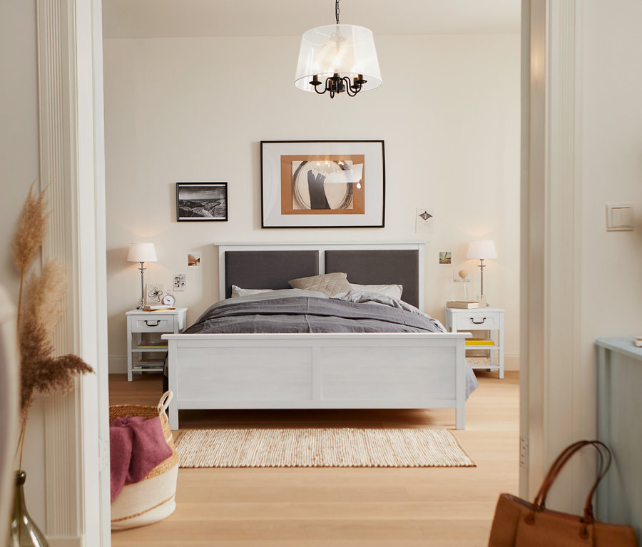 Chambre avec un lit avec tête de lit rembourrée de 160 x 200 cm, une table de chevet à tiroir et une lampe de table avec abat-jour en tissu.