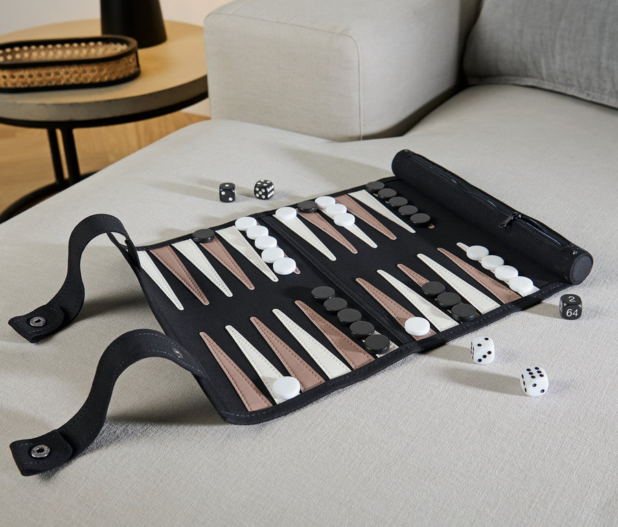 Sur un canapé beige se trouve un jeu de backgammon enroulable ouvert avec des dés.