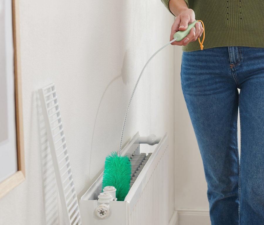 Femme nettoyant un radiateur avec une brosse pour radiateurs.