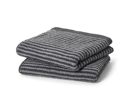 Deux linges de toilette anthracite de haute qualité sont pliés.