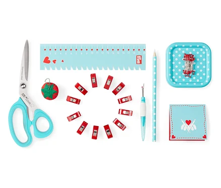 Des ciseaux, des épingles, un mètre, un découd-vite, des pinces et d'autres ustensiles du set de couture Prym Starter-Set Nähen »Love«.