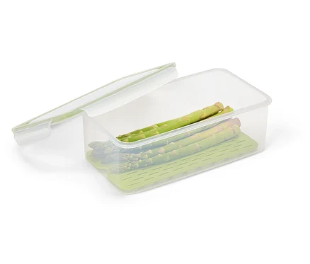 Quelques tiges d'asperges vertes se trouvent dans un récipient alimentaire transparent avec un insert vert et un couvercle transparent.