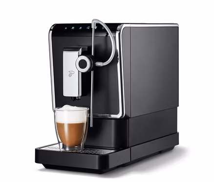 Une machine à café entièrement automatique de Tchibo « Esperto Pro » anthracite avec une tasse de café.