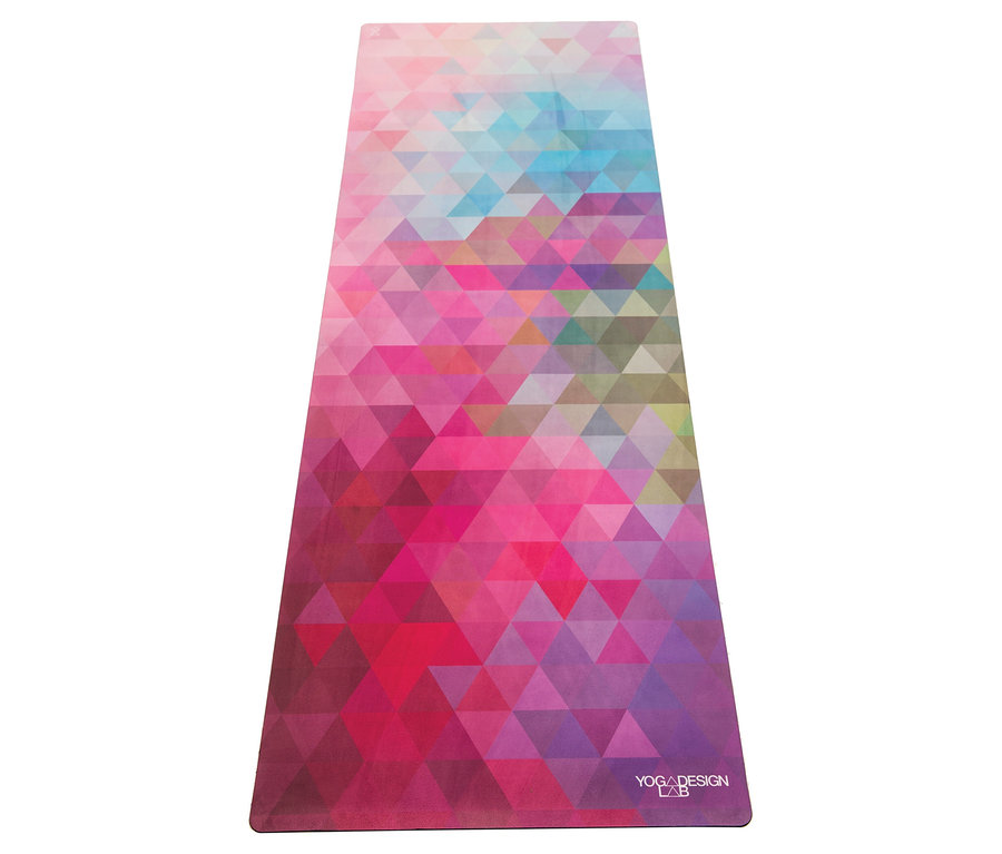 Gros plan d'un tapis de yoga avec un motif géométrique triangulaire dans des tons de rose, violet et bleu.