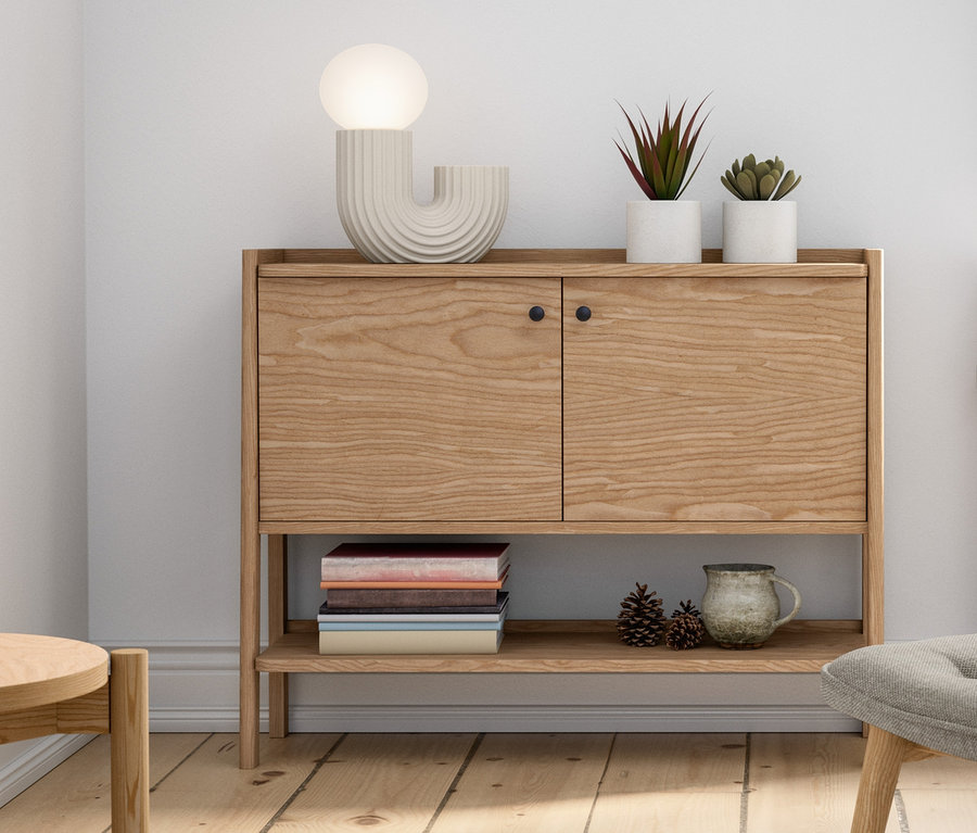 Intérieur avec un buffet en bois, une lampe de bureau design LED, un fauteuil avec repose-pieds, des plantes en pot et des décorations.