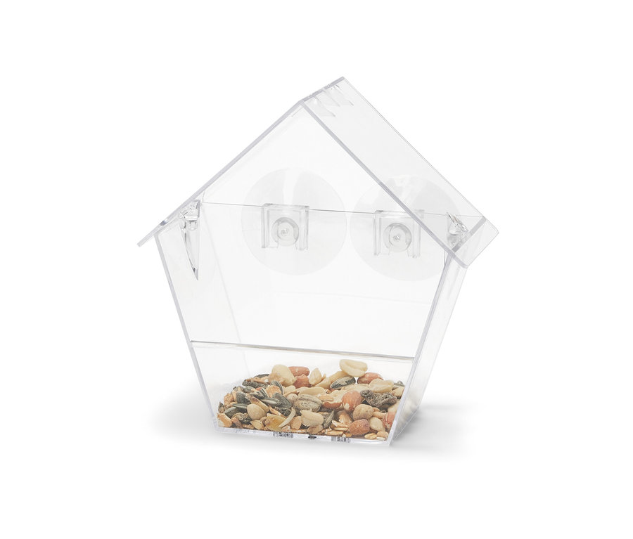 Une mangeoire Ă oiseaux transparente remplie de graines.