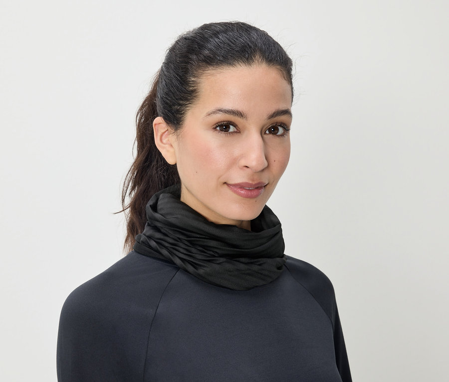 Portrait d'une femme aux cheveux bruns attachés en queue de cheval, portant un pull à col roulé noir.