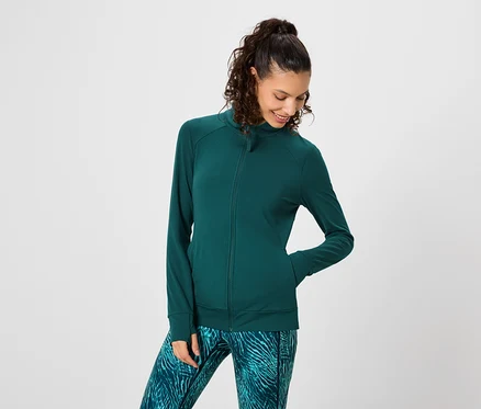 Une femme aux cheveux bouclés foncés porte un survêtement de sport vert et un legging à motifs.