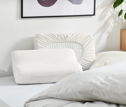Plusieurs oreillers blancs et une taie d'oreiller blanche sont posés sur un lit.