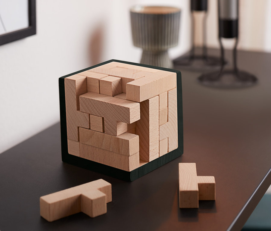 Sur une table, il y a un cube puzzle QI et deux pièces à côté.