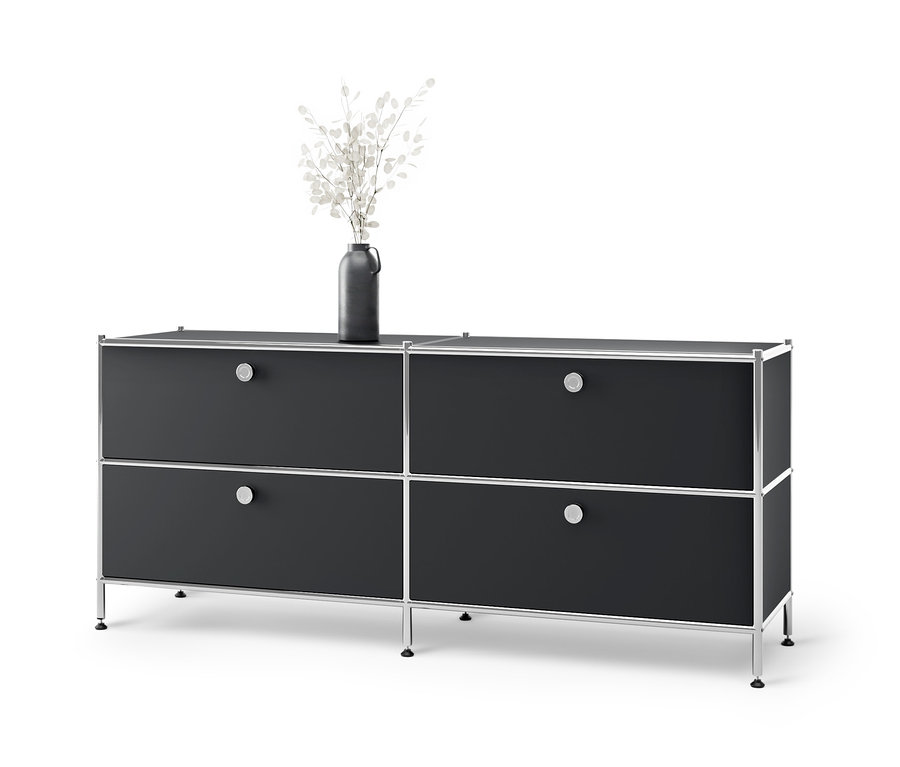 Meuble bas en métal « CN3 » noir avec 4 tiroirs et un vase avec des fleurs blanches sur le dessus.
