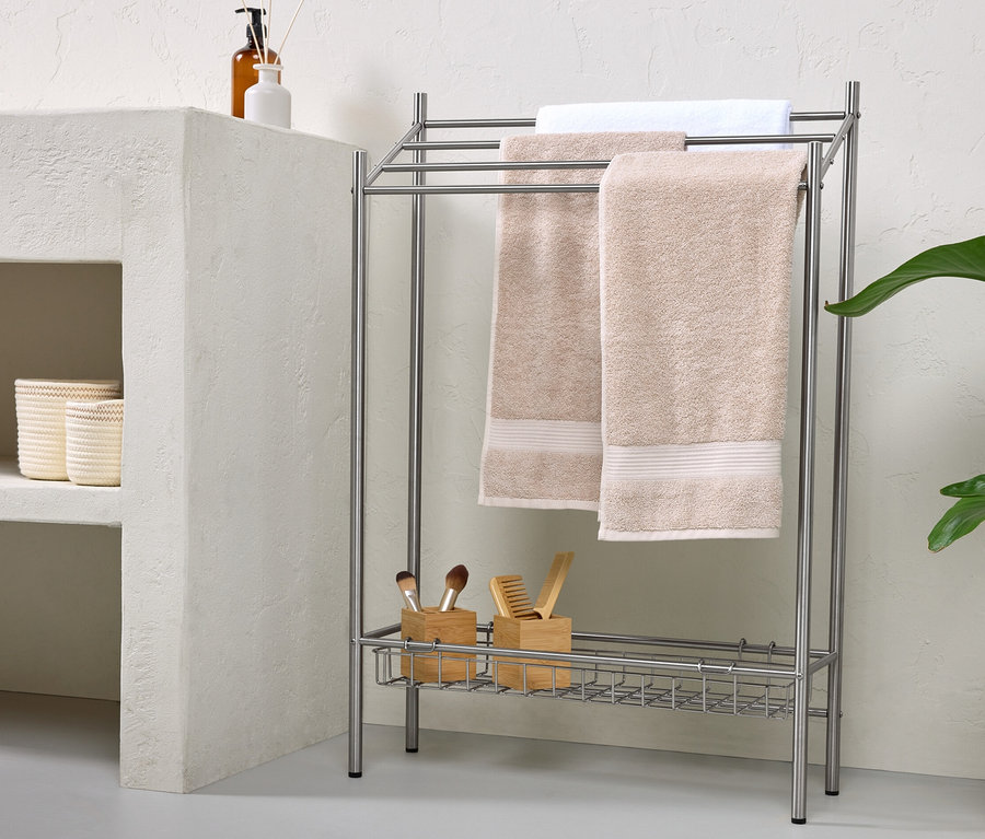 Deux serviettes beiges et une serviette blanche sont suspendues à un porte-serviettes en métal.