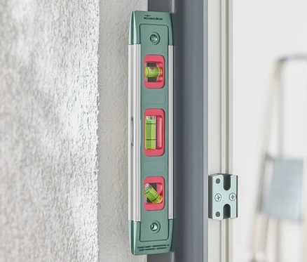 Un niveau magnétique vert est fixé à un mur.
