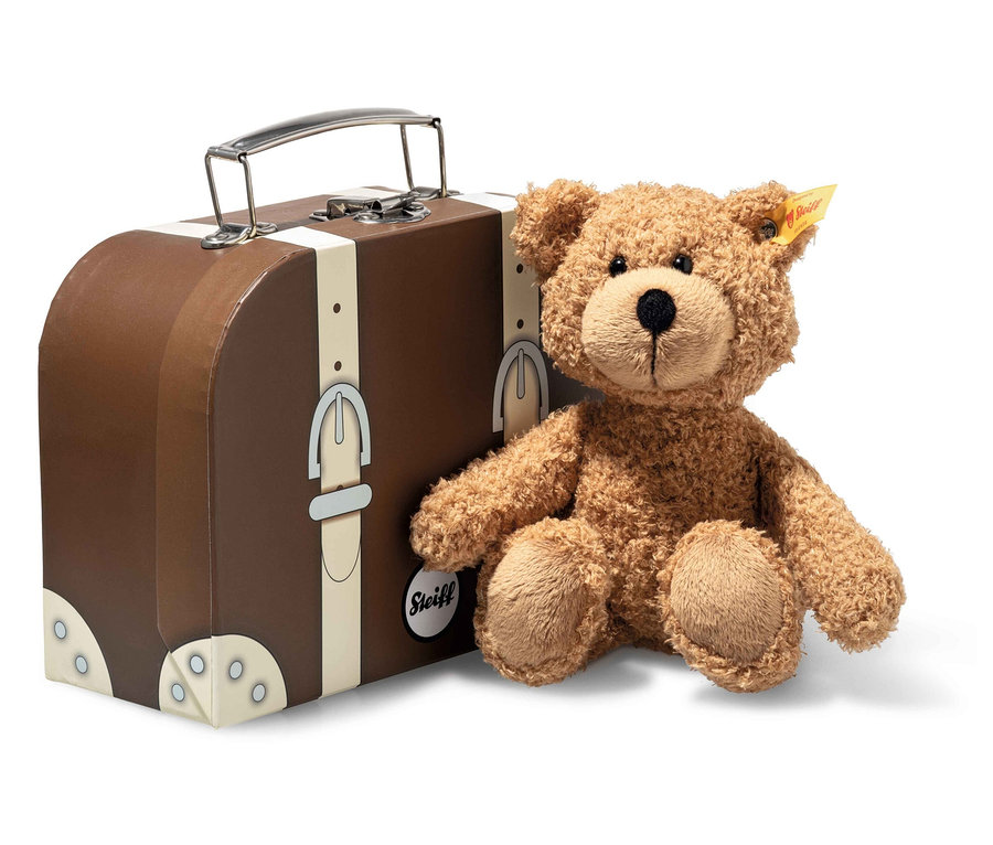Un ours en peluche brun est assis à côté d'une valise marron avec des détails argentés.