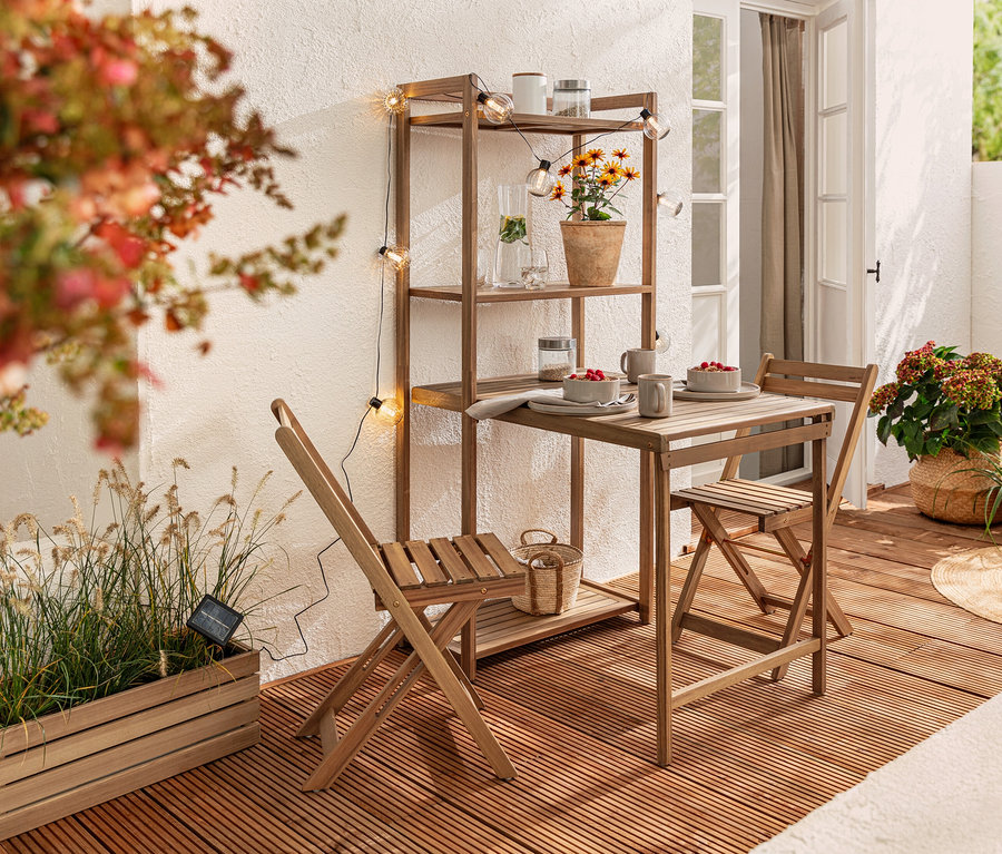 Ensemble de salle à manger de balcon »Lenja« avec étagère et guirlande lumineuse solaire, boules rainurées sur un balcon.