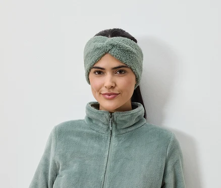 Femme portant un bandeau vert olive et une veste en polaire sur fond blanc.