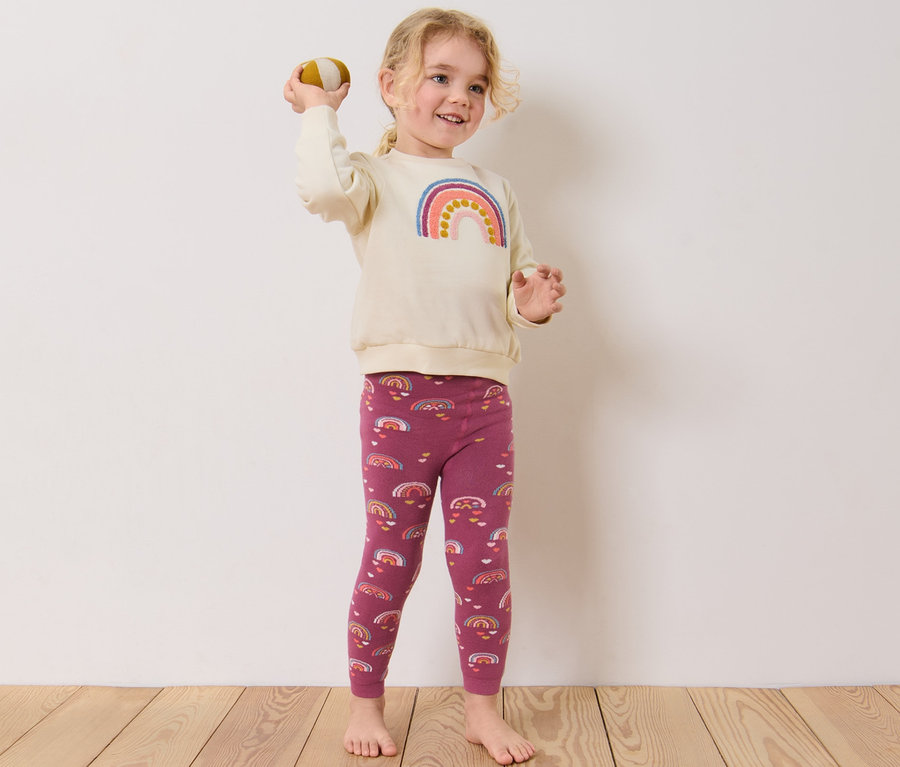 Petite fille lance une balle, porte 2 leggings thermiques pour enfant, rose baie.