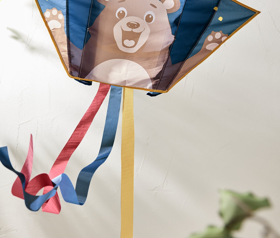 Cerf-volant avec une image d'ours et des rubans colorés flottant derrière.