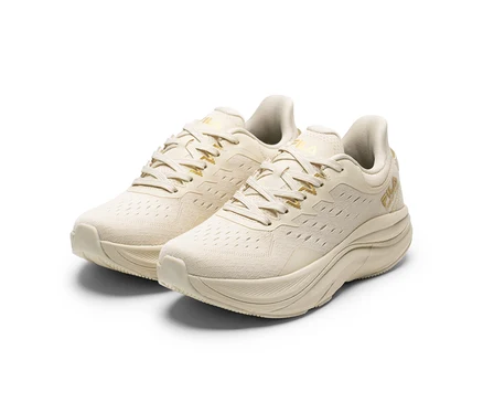 Deux sneakers pour femme FILA Retron de couleur crème avec des accents dorés et des semelles épaisses sur fond blanc.