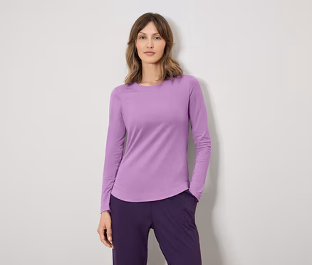 Une femme porte un T-shirt à manches longues violet et un pantalon violet foncé.
