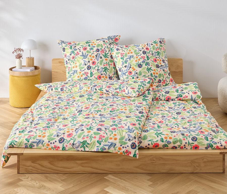 Une parure de lit fleurie repose sur un lit en bois.