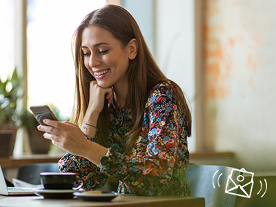 Une femme souriante regarde son smartphone